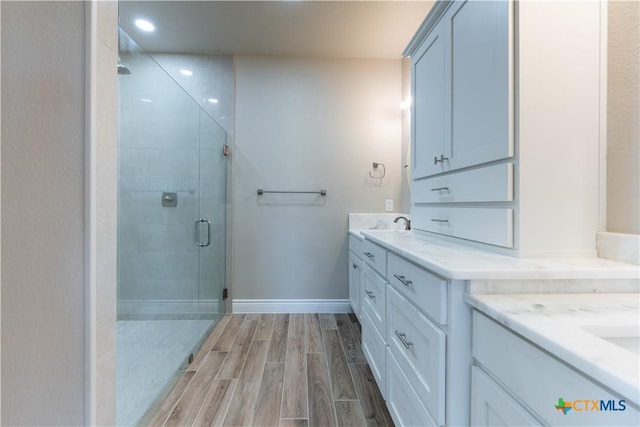 bathroom with vanity, baseboards, wood finish floors, recessed lighting, and a shower stall