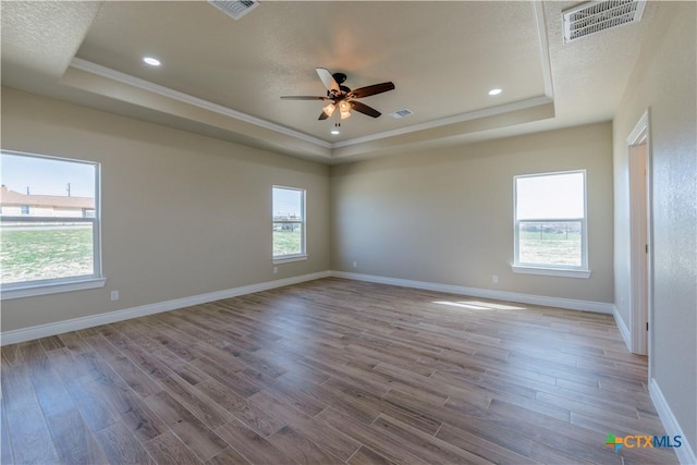 empty room with visible vents, a raised ceiling, and plenty of natural light