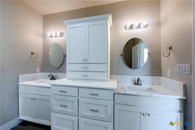 full bathroom with double vanity, baseboards, and a sink