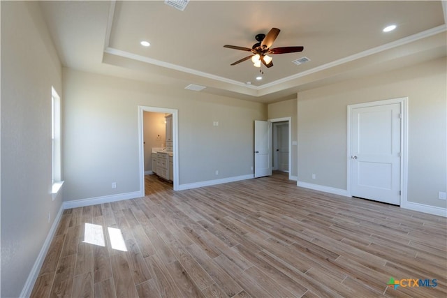 unfurnished bedroom with visible vents, baseboards, light wood-type flooring, and a tray ceiling