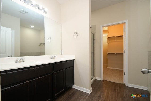 bathroom featuring hardwood / wood-style flooring, a shower with shower door, and vanity