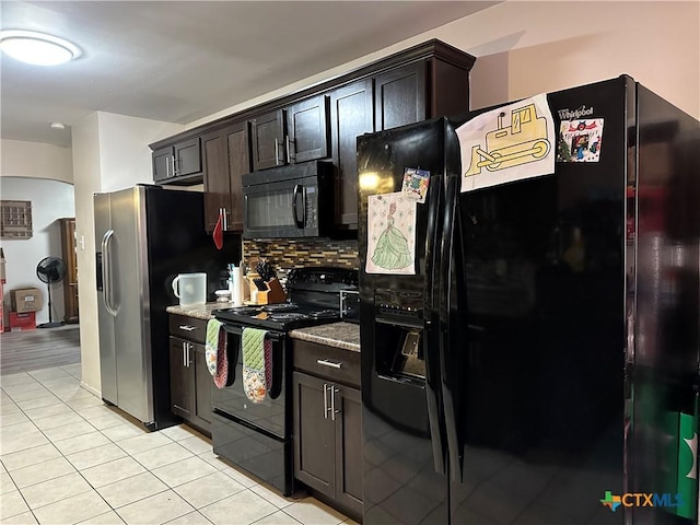 kitchen featuring light tile patterned floors, light stone countertops, dark brown cabinetry, decorative backsplash, and black appliances