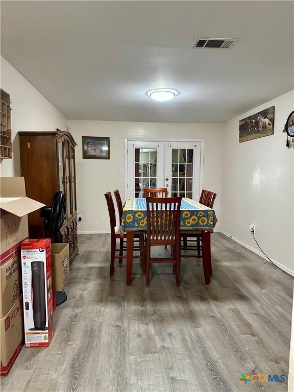 dining area featuring visible vents, baseboards, french doors, and wood finished floors