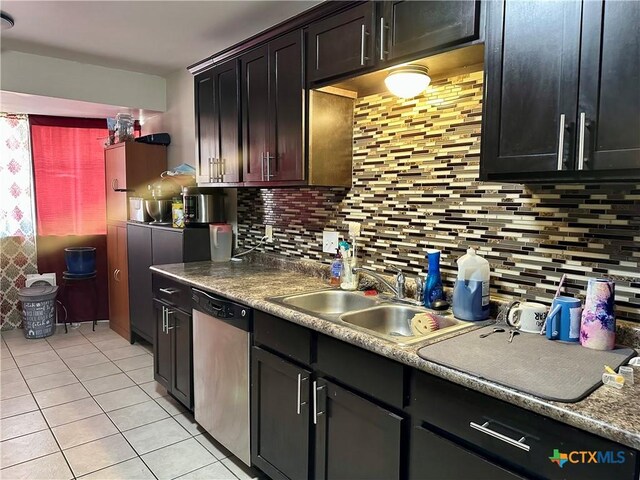 kitchen featuring stainless steel dishwasher, a sink, light tile patterned floors, and tasteful backsplash