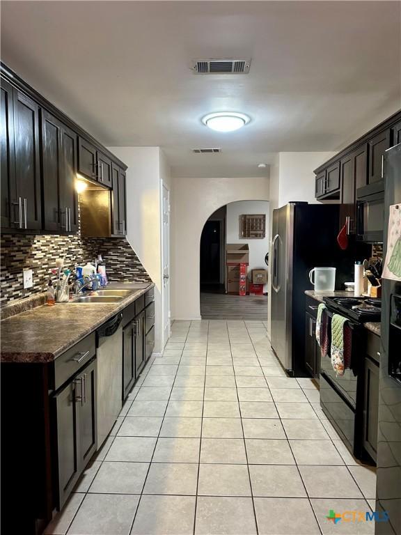 kitchen featuring black appliances, arched walkways, a sink, and visible vents