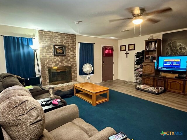 living room with a fireplace, wood finished floors, and a ceiling fan
