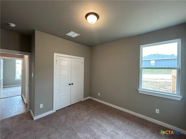 unfurnished bedroom featuring carpet, a textured ceiling, and a closet