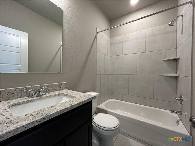 full bathroom featuring tiled shower / bath, vanity, and toilet