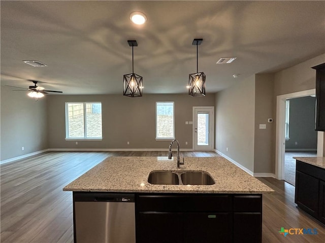 kitchen with a kitchen island with sink, sink, light stone countertops, and dishwasher