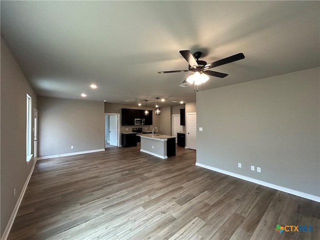 unfurnished living room featuring sink, dark wood-type flooring, and ceiling fan