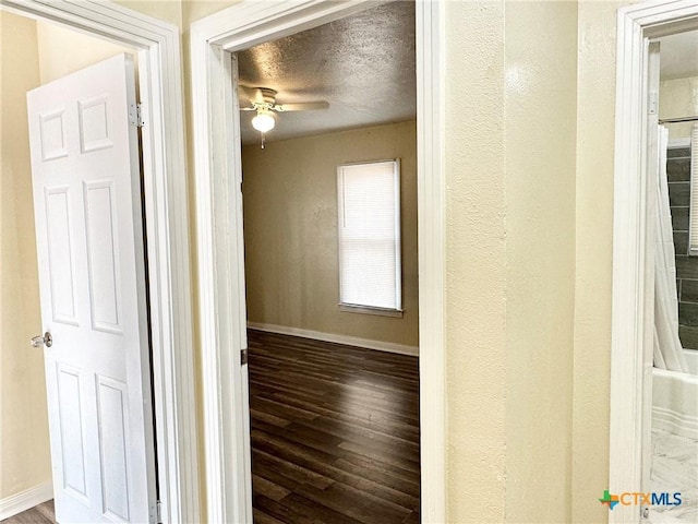 corridor with a textured ceiling and hardwood / wood-style flooring