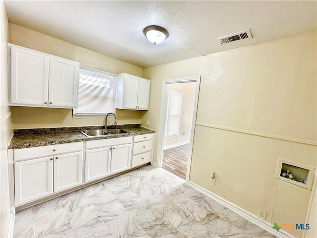 kitchen featuring white cabinets, sink, and a textured ceiling