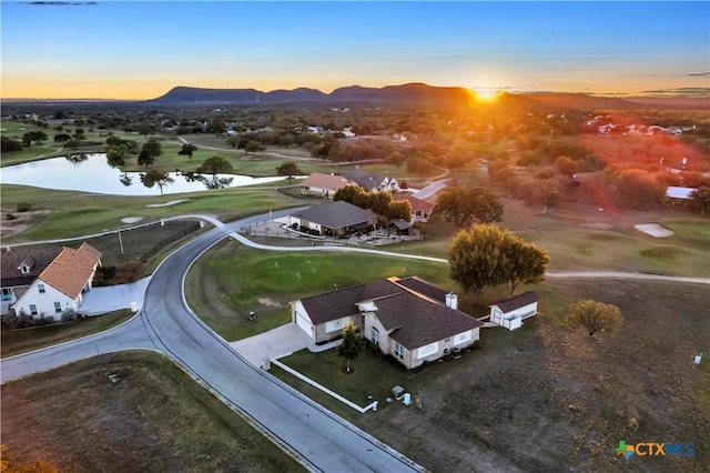 aerial view at dusk featuring a water and mountain view