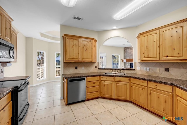 kitchen with tasteful backsplash, sink, light tile patterned floors, and appliances with stainless steel finishes