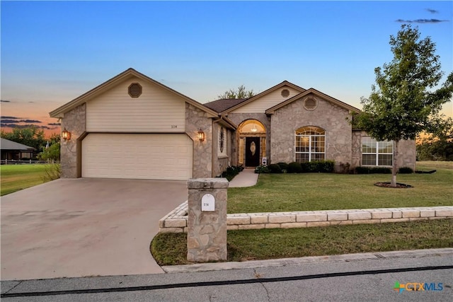 ranch-style home featuring a lawn and a garage