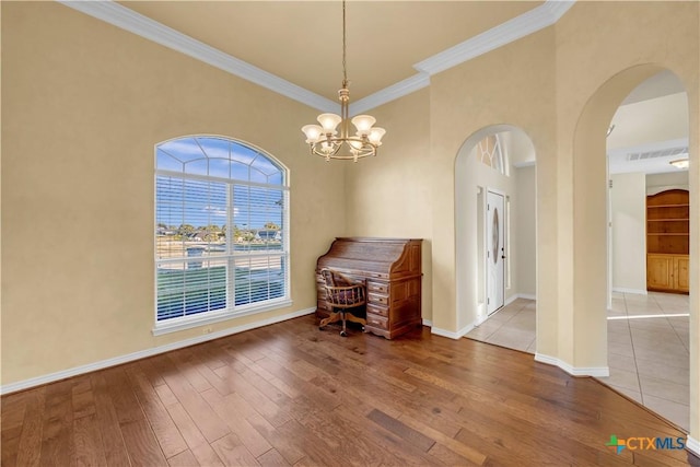 unfurnished dining area with hardwood / wood-style flooring, crown molding, and an inviting chandelier