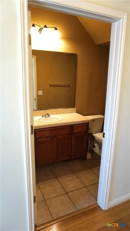 bathroom featuring vanity, lofted ceiling, toilet, and tile patterned flooring