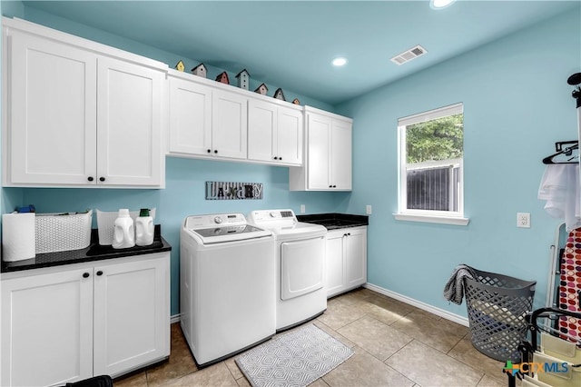 clothes washing area featuring cabinets, washer and clothes dryer, and light tile patterned flooring