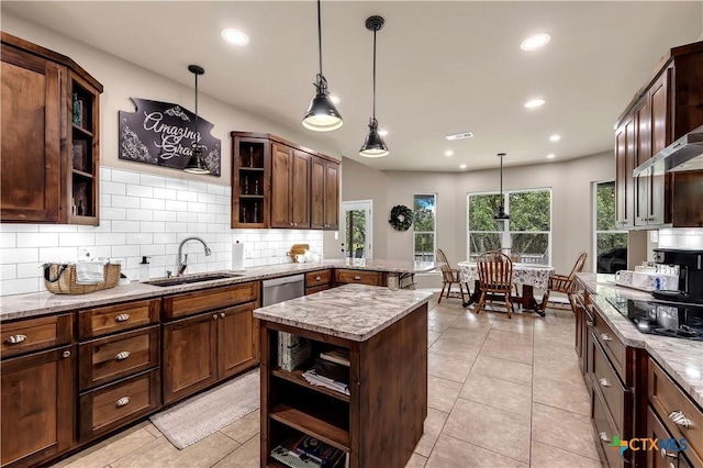 kitchen with light stone countertops, stainless steel dishwasher, sink, pendant lighting, and light tile patterned floors