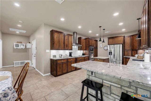 kitchen with a breakfast bar, wall chimney range hood, sink, decorative backsplash, and appliances with stainless steel finishes