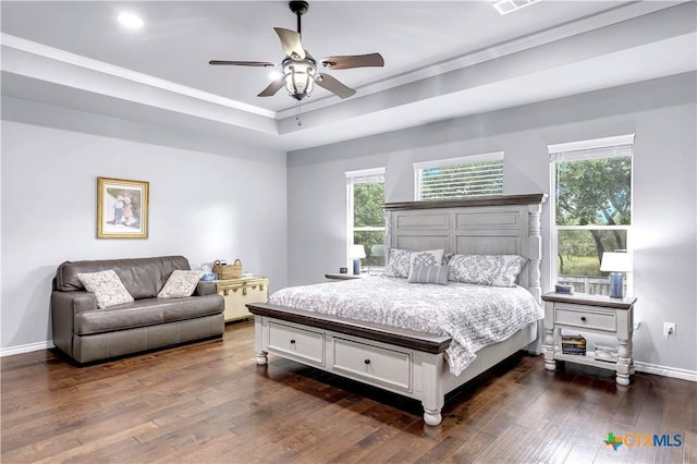 bedroom with a tray ceiling, crown molding, ceiling fan, and dark wood-type flooring