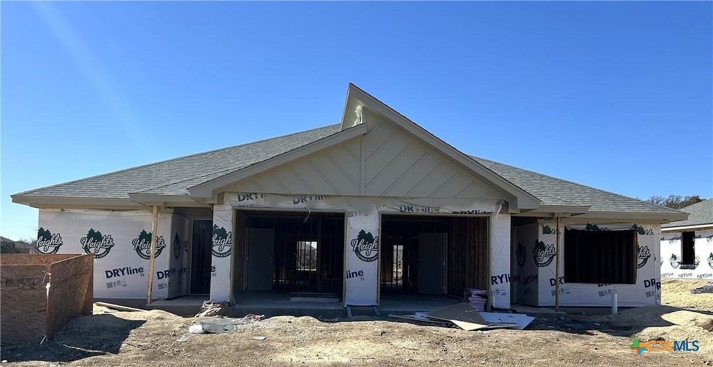 property in mid-construction featuring a garage and a shingled roof