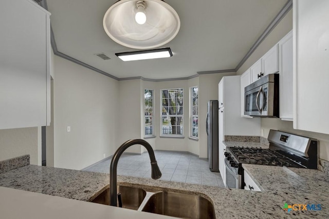 kitchen with sink, white cabinetry, crown molding, light stone counters, and appliances with stainless steel finishes