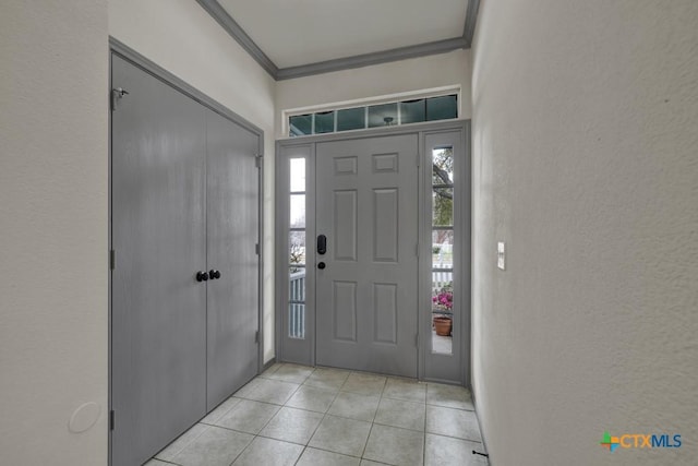 foyer entrance featuring light tile patterned flooring and ornamental molding