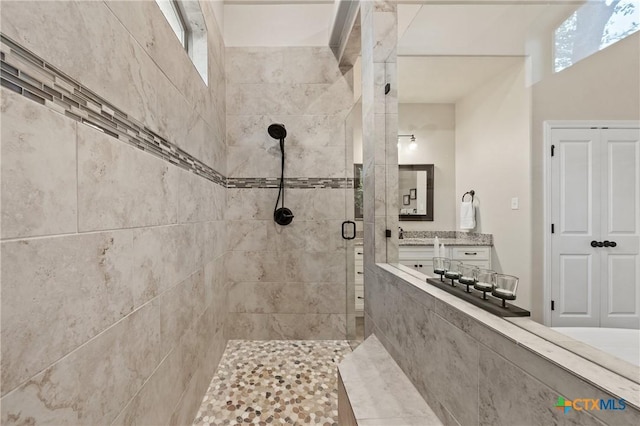 full bathroom with a tile shower and vanity