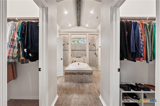 bathroom featuring vaulted ceiling with beams, a walk in closet, tiled shower, and wood finished floors