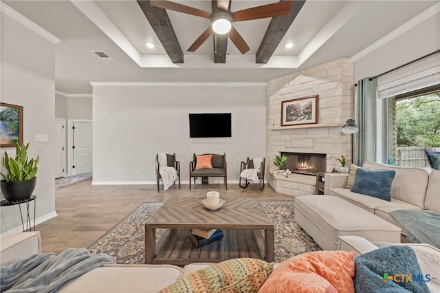 living room featuring visible vents, ornamental molding, a stone fireplace, beamed ceiling, and baseboards