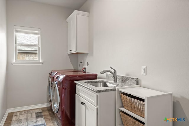 laundry room with cabinet space, light wood-style floors, a sink, washer and dryer, and baseboards