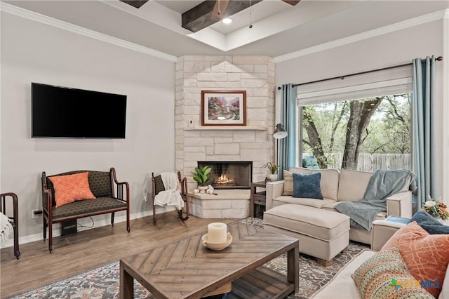 living area featuring beam ceiling, a fireplace, ornamental molding, wood finished floors, and baseboards