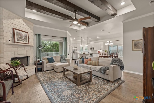 living area with light wood-style floors, a fireplace, baseboards, and beam ceiling