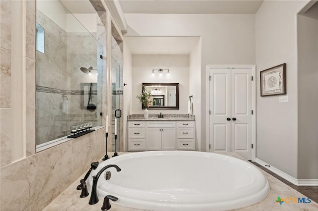 full bathroom with vanity, a shower stall, baseboards, and a bath