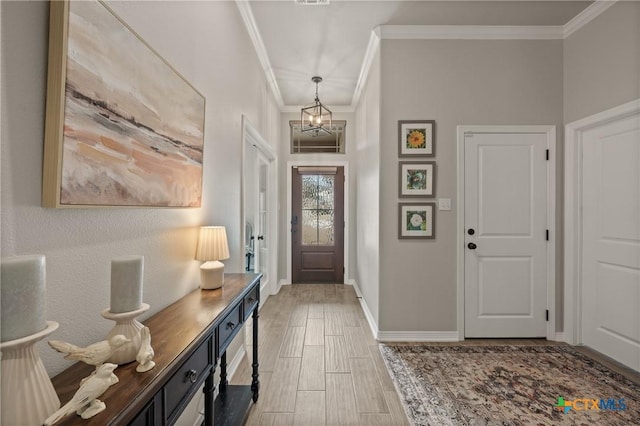 foyer entrance featuring light wood finished floors, baseboards, crown molding, and an inviting chandelier