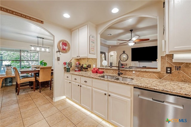 kitchen with stainless steel dishwasher, a sink, ceiling fan, arched walkways, and backsplash