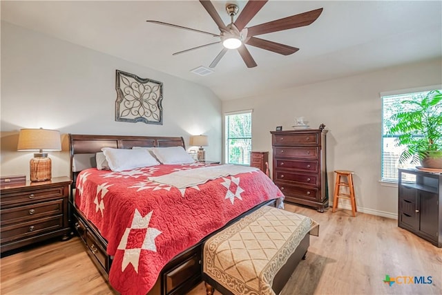 bedroom featuring vaulted ceiling, light wood-type flooring, multiple windows, baseboards, and ceiling fan
