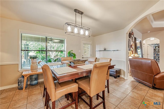 dining area with arched walkways, light tile patterned floors, and baseboards