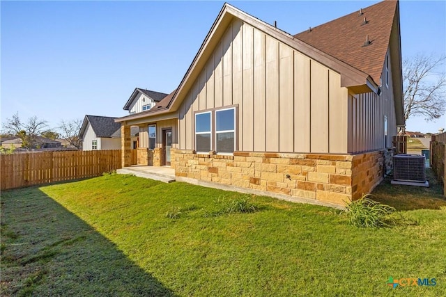 back of house with cooling unit and a lawn