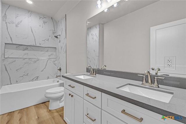 full bathroom featuring hardwood / wood-style floors, vanity, toilet, and tiled shower / bath