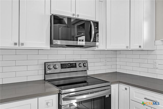 kitchen with white cabinets, appliances with stainless steel finishes, and backsplash