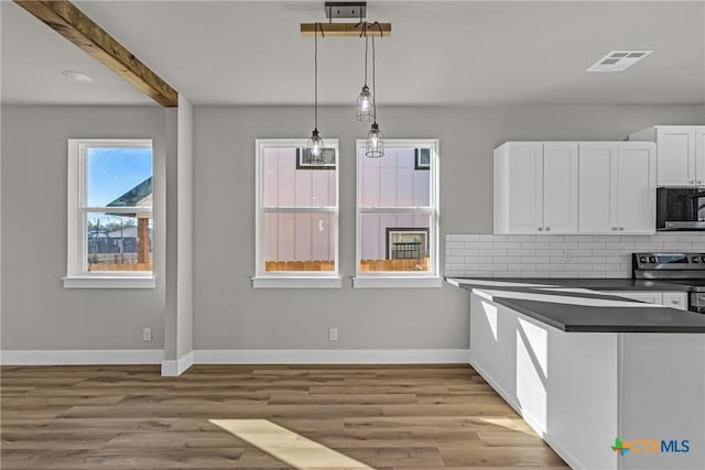 kitchen featuring white cabinets, backsplash, hanging light fixtures, and light hardwood / wood-style flooring