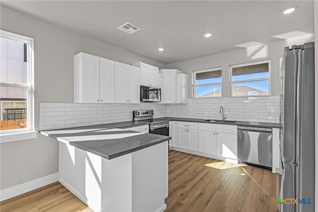 kitchen featuring sink, white cabinetry, appliances with stainless steel finishes, light hardwood / wood-style floors, and kitchen peninsula