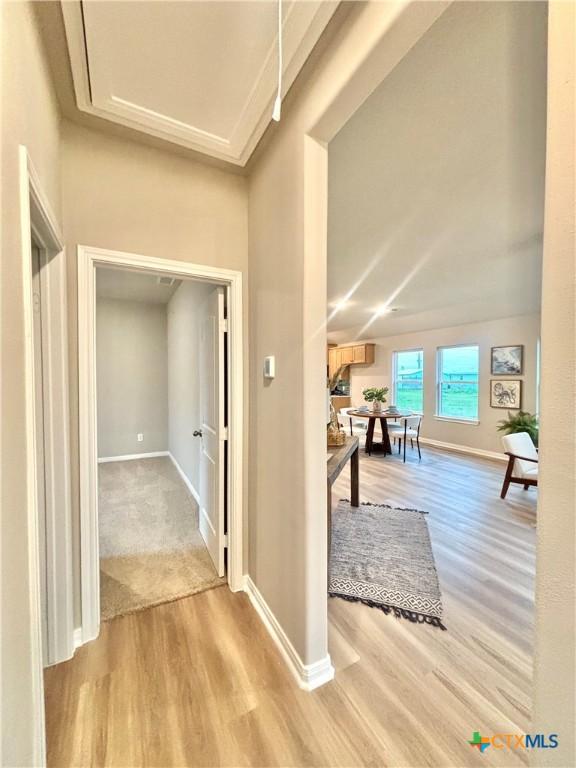 corridor with light wood-style flooring and baseboards