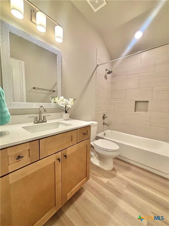 full bath with visible vents, toilet, wood finished floors, tub / shower combination, and vanity