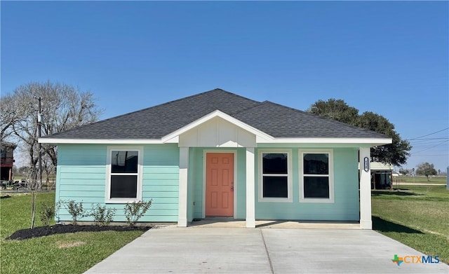 bungalow-style home with a shingled roof, a front yard, and board and batten siding