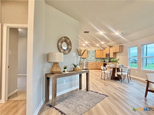 kitchen featuring visible vents, backsplash, appliances with stainless steel finishes, light wood-style floors, and light brown cabinets