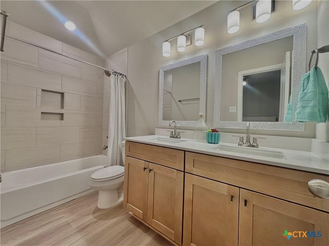 full bath with toilet, shower / tub combo, a sink, and wood finished floors