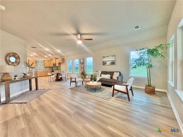 living area featuring light wood-type flooring, visible vents, ceiling fan, and baseboards